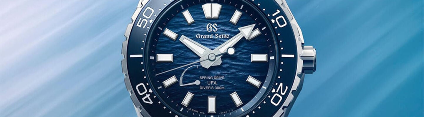Close-up banner of a blue Grand Seiko Spring Drive UFA diver&rsquo;s watch with textured ocean-inspired dial, silver markers, and rotating bezel against a soft blue gradient background.